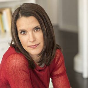 Headshot of author Nell Freudenberger, a White woman wearing a red top